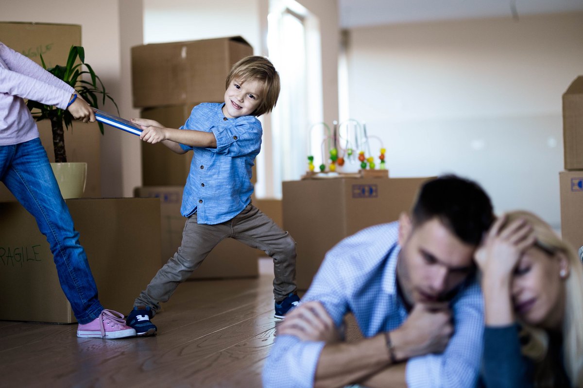 Streitende Kinder im Vordergrund verzweifelnde Eltern