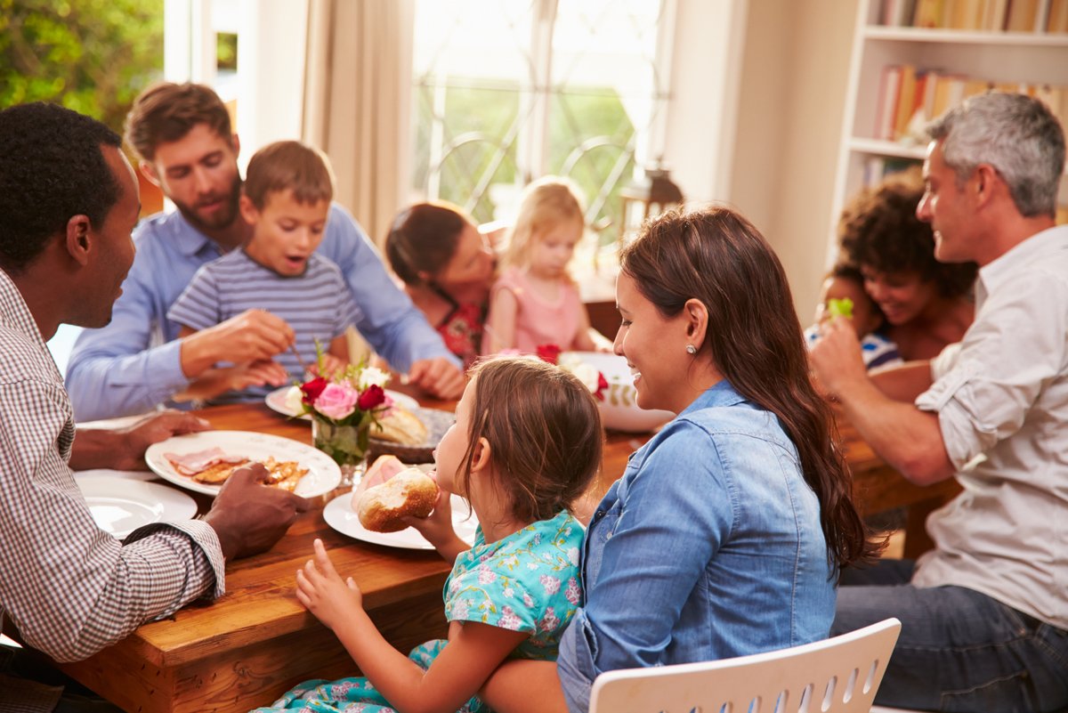 Erwachsene und Kinder essen gemeinsam an einem grossen Tisch.