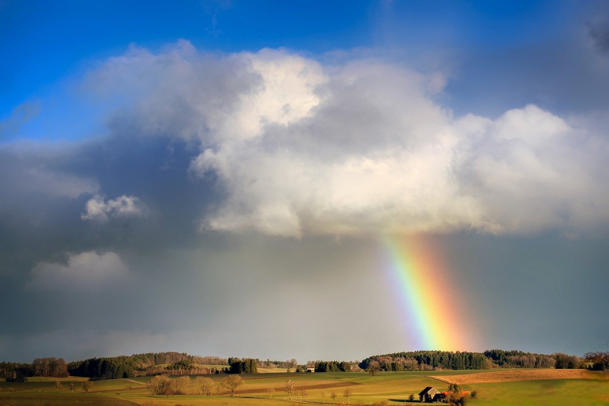 Regenbogen aus Wolken über Feldlandschaft