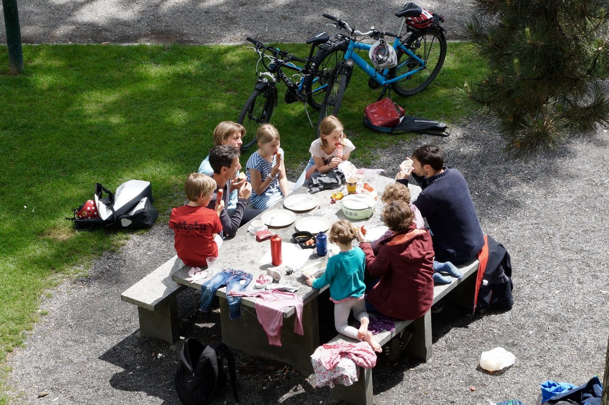 Erwachsene und Kinder sitzen draussen an einem Tisch.