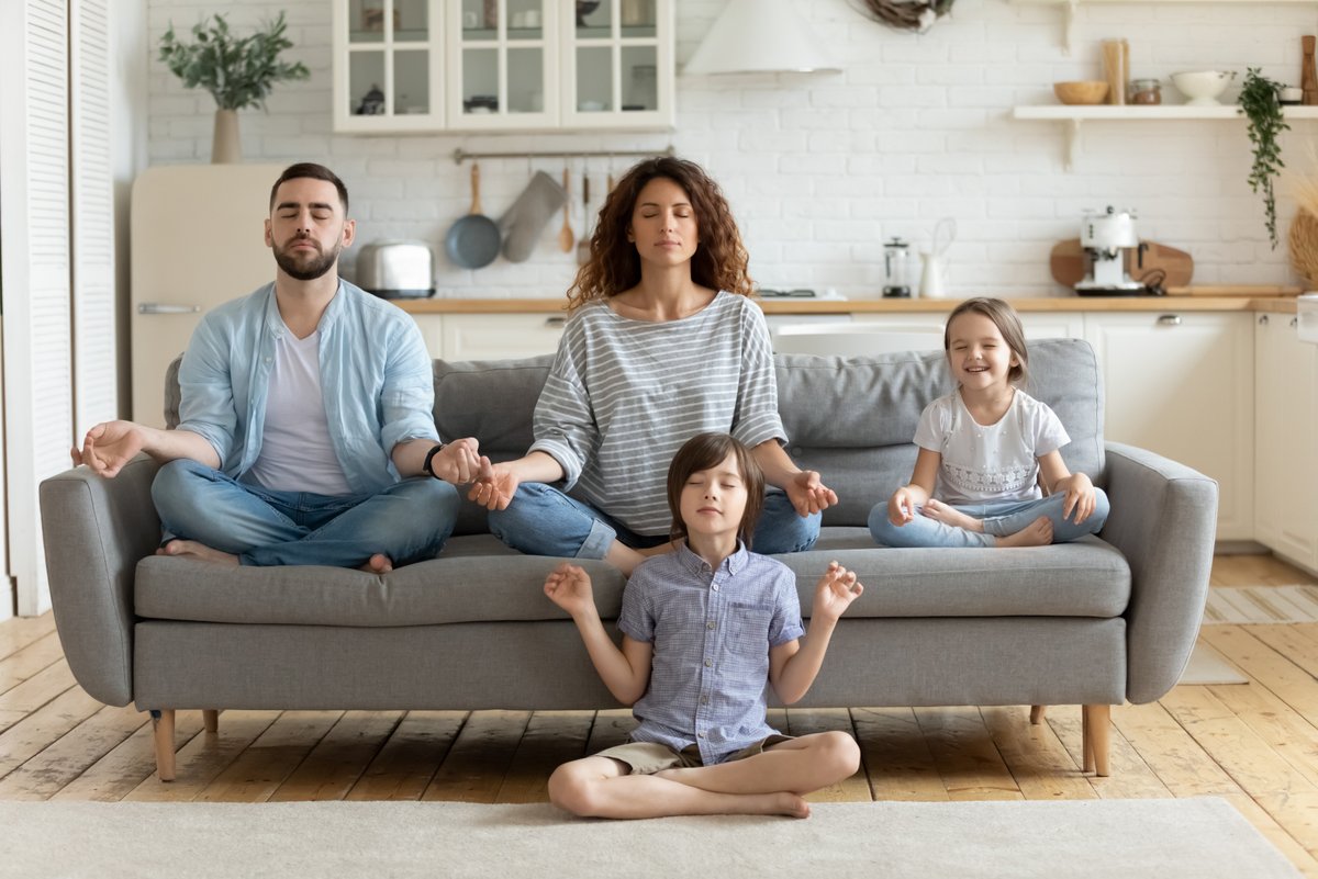 Mann, Frau, junges Mädchen aus Sofa sitzend und in Meditationhaltung. Jungebsitzend vor dem Sofa.